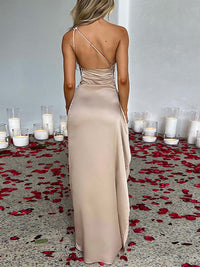 Frau im eleganten, beigen Abendkleid mit Kerzen und Rosenblättern auf dem Boden.