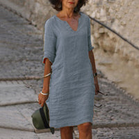 Frau in grauem Leinenkleid, V-Ausschnitt, Sommermode, lässig, stilvoll, Gehweg.